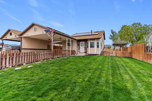 Rear view of house featuring roof mounted solar panels, a carport, and a patio area