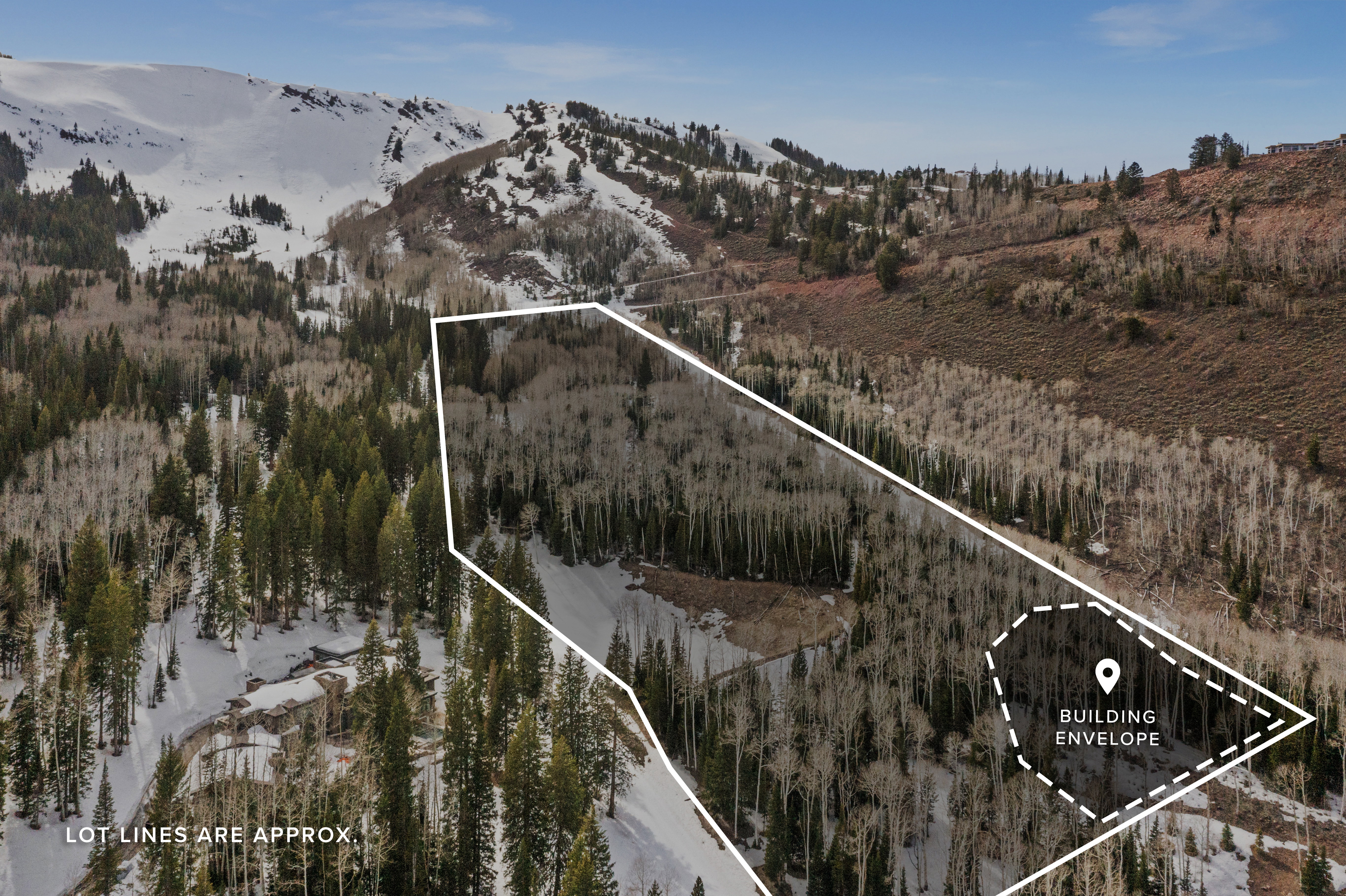 Aerial view of property and surrounding area with a mountain backdrop and property parcel outlined
