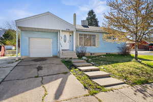View of front facade featuring an attached garage, driveway, and a chimney