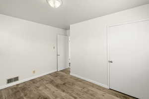 Unfurnished bedroom with wood finished floors and baseboards