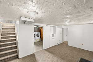 Finished below grade area featuring a textured ceiling, dark carpet, and washer and dryer