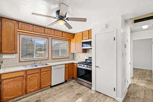 Kitchen with light countertops, stainless steel appliances, ceiling fan, and light wood finished floors