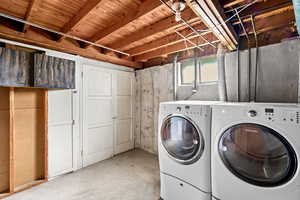 Laundry area featuring unfinished concrete flooring and washer and clothes dryer