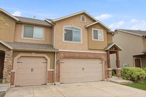 Traditional home featuring stucco siding, driveway, an attached garage, and brick siding