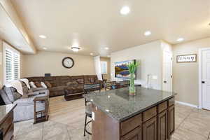 Kitchen featuring a center island, a breakfast bar, light tile patterned flooring, open floor plan, and dark stone counters