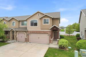Traditional-style home featuring an attached garage, brick siding, driveway, stucco siding, and a shingled roof