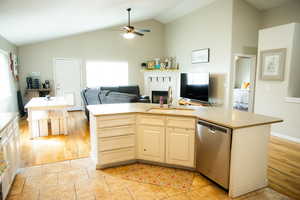 Kitchen featuring a kitchen island with sink, open floor plan, dishwasher, light countertops, and lofted ceiling