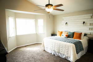 Bedroom with vaulted ceiling, carpet flooring, and a ceiling fan