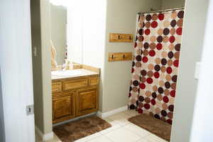 Full bathroom with vanity, curtained shower, and light tile patterned flooring