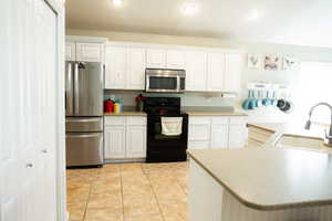 Kitchen with stainless steel appliances, white cabinetry, light tile patterned flooring, and recessed lighting