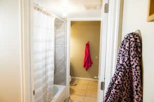 Bathroom featuring light tile patterned flooring and shower / tub combo with curtain