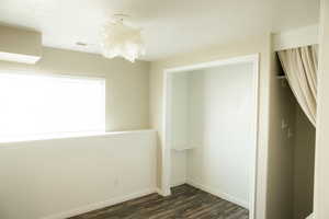 Unfurnished bedroom featuring dark wood-style flooring and baseboards