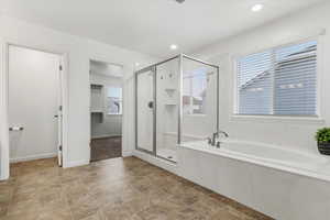 Full bathroom featuring a shower stall, a garden tub, stone finish flooring, recessed lighting, and a walk in closet