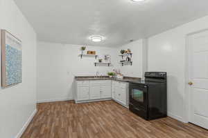 Kitchen with white cabinetry, black electric range, open shelves, dark wood-type flooring, and a textured ceiling