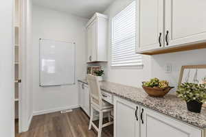 Laundry area featuring dark wood finished floors and baseboards