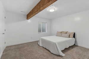 Bedroom featuring beam ceiling, carpet floors, and a textured ceiling