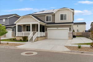 Craftsman house featuring board and batten siding, huge covered porch, roof mounted solar panels, stone siding, and driveway and RV parking