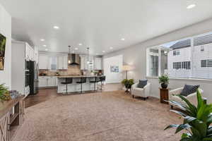 Living area with recessed lighting and dark colored carpet