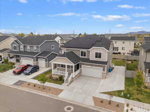 View of front of home featuring solar panels, stone siding, roof with shingles, and a residential view