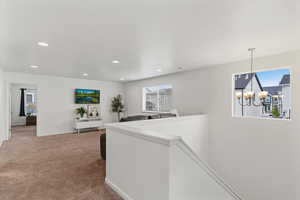 Hall with a chandelier, carpet, and an upstairs landing