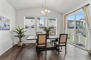 Dining space with plenty of natural light, vaulted ceiling, suspended lighting, and dark wood finished floors
