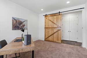 Home office with dark carpet and a barn door