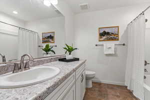 Full bath featuring vanity, shower / tub combo, and stone finish flooring
