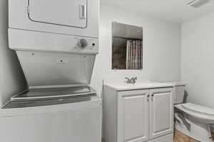 Bathroom featuring vanity, curtained shower, and stacked washing machine and dryer