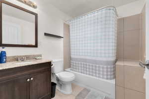 Full bath with vanity, shower / bath combo with shower curtain, and light tile patterned flooring