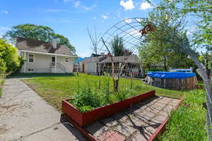 Rear view of house with a lawn, a chimney, and a vegetable garden