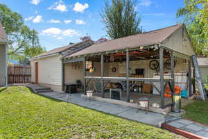Rear view of property featuring a shingled roof and a patio area