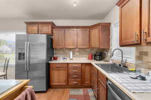 Kitchen with stainless steel appliances, wood finish cabinetry, and backsplash