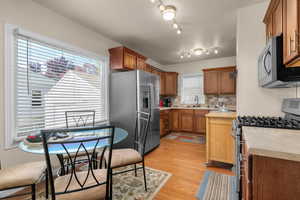 Kitchen featuring stainless steel appliances, wood finish cabinetry, backsplash, light wood-type flooring, and wooden counters