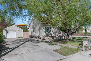 View of front facade featuring a gate, concrete driveway, a detached garage, and an outdoor structure