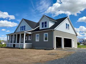 View of side of home with covered porch, gravel driveway, an attached garage, a mountain view, and a shingled roof
