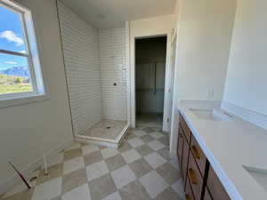 Bathroom featuring double vanity, a spacious closet, a tile shower, light floors, and a mountain view