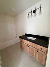 Full bath with vanity, light tile patterned floors, and shower / bathtub combination