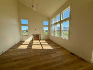 Unfurnished living room with vaulted ceiling, ceiling fan, and light wood-style floors. Mantle will be installed