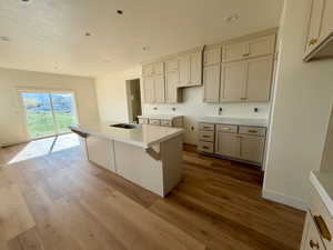 Kitchen with a center island with sink, light countertops, light wood-type flooring, a breakfast bar area, and recessed lighting