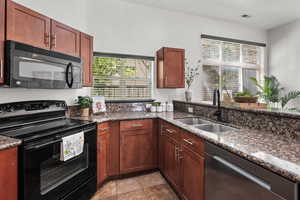 Kitchen featuring black appliances and dark stone counters