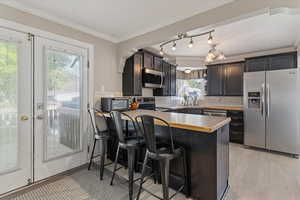 Kitchen featuring stainless steel appliances, a breakfast bar, light countertops, crown molding, and a peninsula