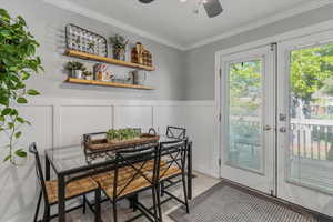 Dining area featuring a decorative wall, ceiling fan, a wainscoted wall, ornamental molding, and light wood-type flooring