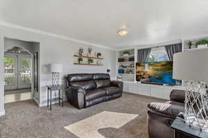 Living area with light carpet, a textured ceiling, healthy amount of natural light, french doors, and ornamental molding