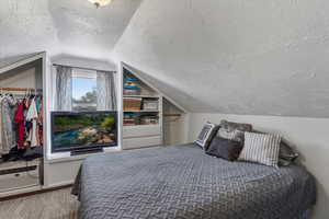 Bedroom featuring a textured ceiling and an AC wall unit