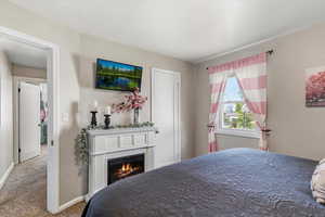 Bedroom with carpet flooring and a lit fireplace