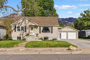 View of front of house featuring a mountain view, a front yard, a garage, and an outdoor structure
