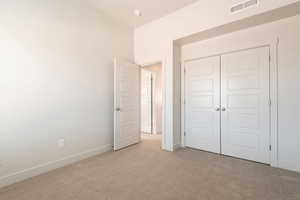 Unfurnished bedroom with light colored carpet and a closet