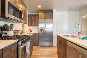 Kitchen with stainless steel appliances, light wood-type flooring, wood finish cabinets, backsplash, and recessed lighting
