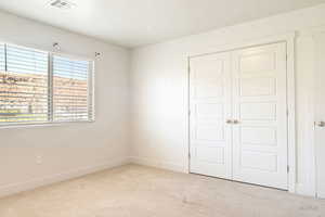 Unfurnished bedroom with light carpet and a closet
