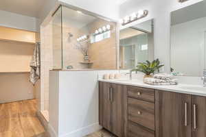 Full bathroom featuring double vanity, light wood finished floors, and walk in shower